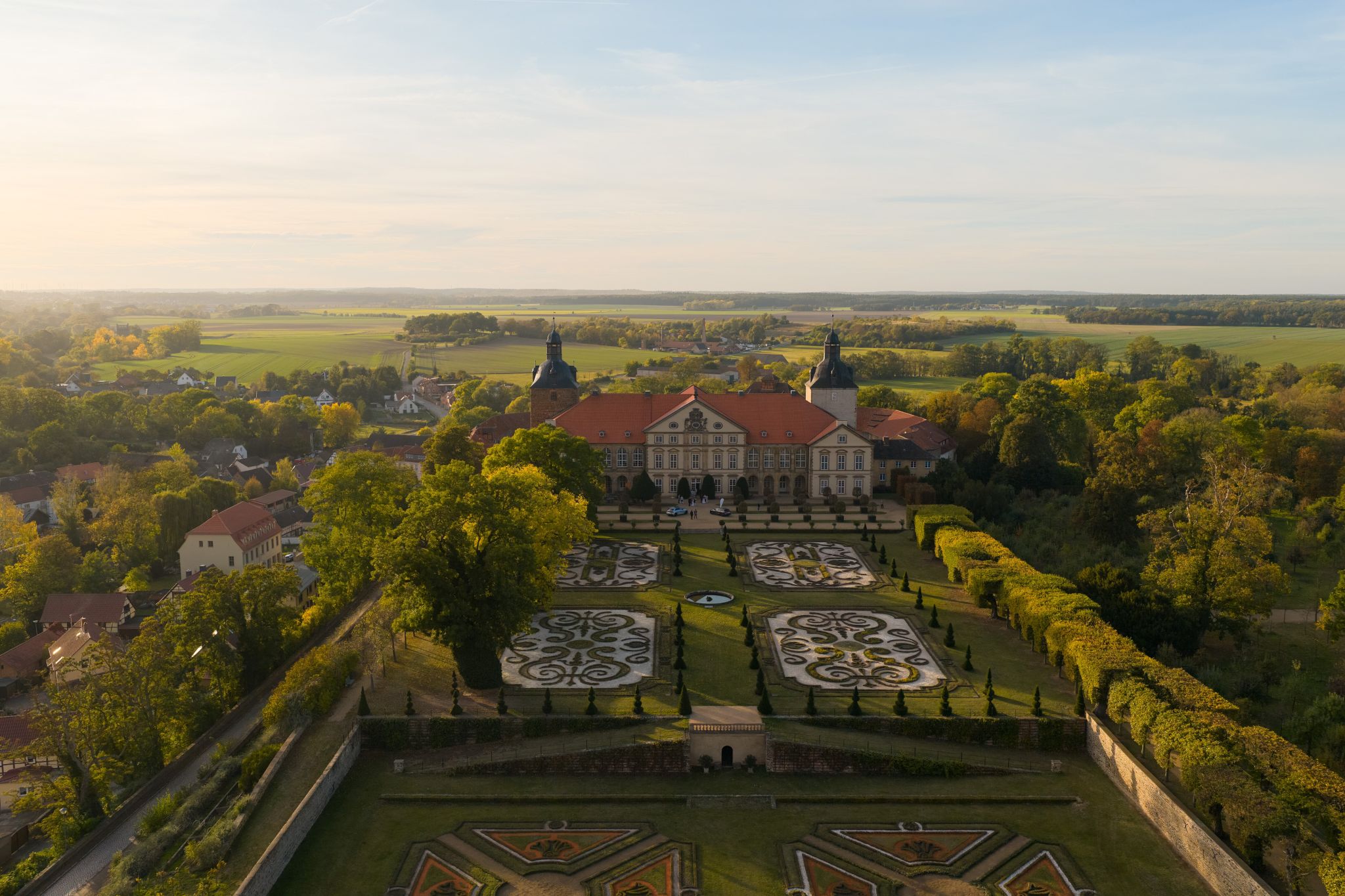 Luftaufnahme von Schloss Hundisburg mit Barockgarten im Abendlicht